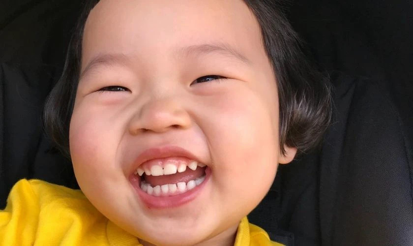 Meme em bé đang cười với ánh mắt tinh nghịch